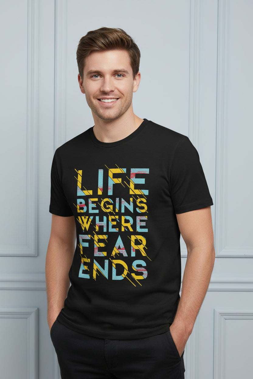 A black short-sleeve crewneck t-shirt featuring a colorful graphic text print that reads 'LIFE BEGINS WHERE FEAR ENDS' in yellow, blue, and white distressed lettering with yellow lightning accents, shown on a plain white background.