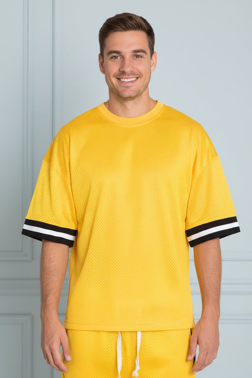 Person wearing a yellow sports outfit with black trim on a white background